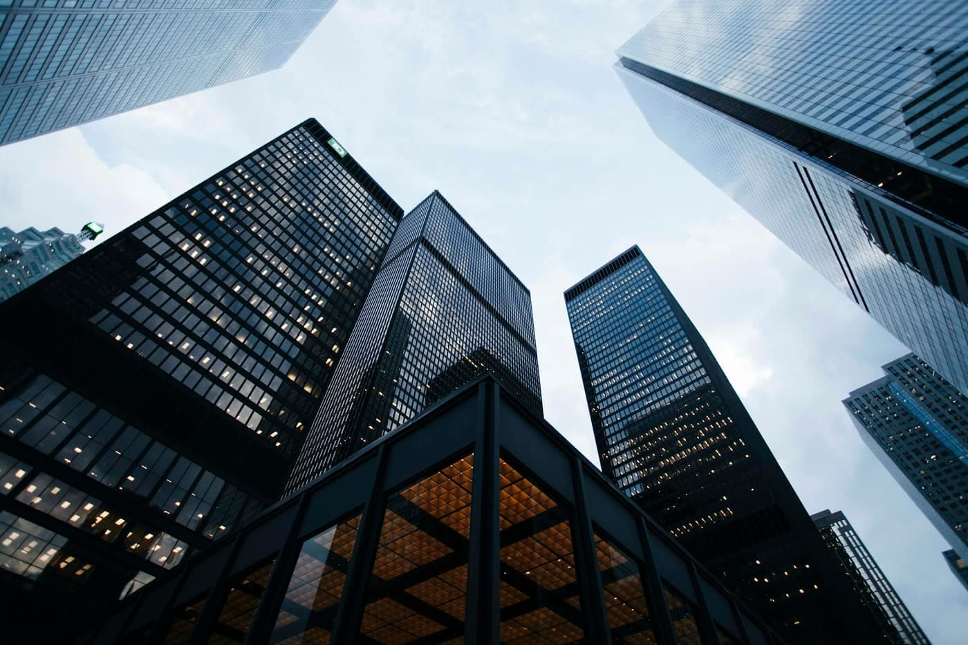 Glass office towers of a business district shot from below: the corporate property whose continuity insurance protects